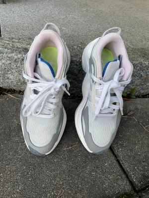 Adidas runner i vit/grå - Fräscha Adidas sneakers med chunky sula. Färgerna är vitt, ljusgrått och detaljer i blått och mintgrönt. Insidan har ljusrosa foder och märkning på hälen. Knappt använda!