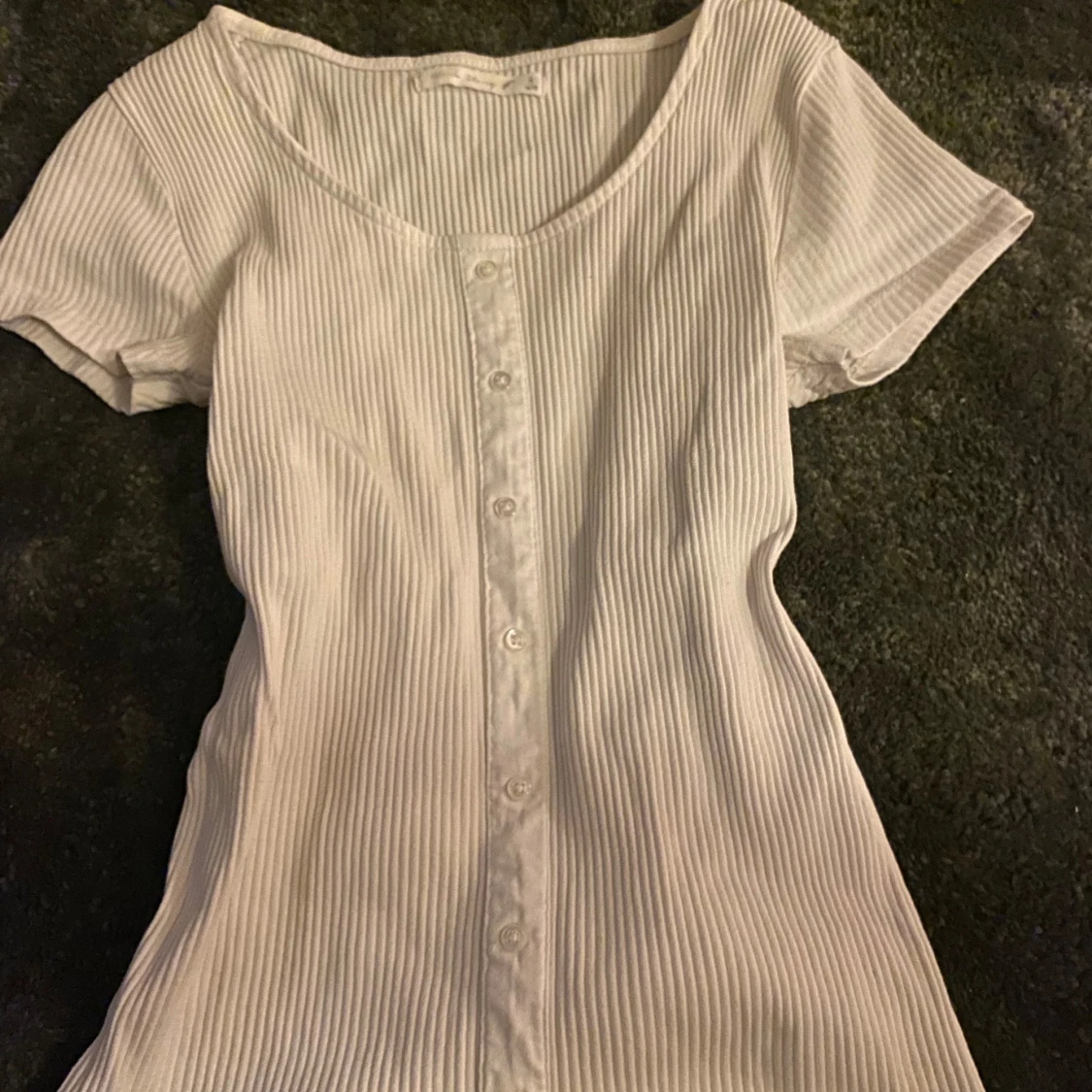 Vit ribbad topp med knappar .