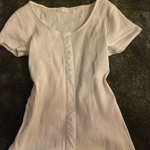 Vit ribbad topp med knappar . - Säljer en vit ribbad topp från black slary  i storlek S. 