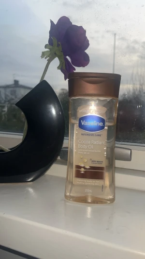 Vaseline Cocoa Radiant Body Oil 200ml - Vaseline Intensive Care Cocoa Radiant Body Oil med ren kakaosmör och återfuktande oljor. Kommer i en genomskinlig plastflaska med bronsfärgat lock.                                                Perfekt för dig som vill ha återfuktad och strålande hud. 