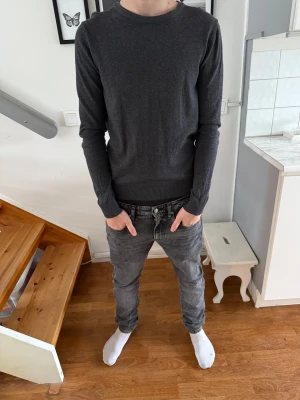 Mörkgrå stickad tröja Jack & Jones  - Snygg mörkgrå stickad tröja från Jack & Jones i storlek XS men passar S. Tröjan har rund hals, ribbade muddar och nederkant samt långärmad passform. Perfekt för dig som gillar stilrena och enkla plagg med skön känsla. Passar dig som vill ha en normal passning.