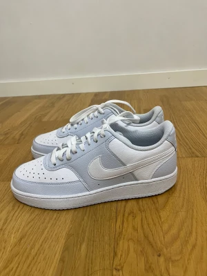 Nike Air Force 1 sneakers vit/grå - Fräscha Nike Air Force 1 sneakers i vit och ljusgrå färg med klassisk låg siluett. Skorna har snörning, perforerad tå och är tillverkade i skinn med syntetdetaljer. Swoosh-loggan på sidan och platt sula ger en clean och stilren vibe. Aldrig använt och är i storlek 41 men kan passa 40/5 finns i Hudiksvall men kan även postas 😊💝