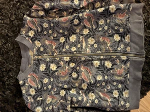 Blommig ”inne”jacka från Lindex - Säljer en snygg ”innerjacka”/kofta från Lindex med blommigt och fågelmönster i ljus blå/grå, rosa och vitt. Jackan har ribbade muddar, dragkedja framtill och är tillverkad i mjuk bomull. Perfekt för dig som gillar färg och coola prints.