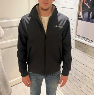 Svart Sail Racing Gore-Tex jacka - Svart vindjacka från Sail Racing i Gore-Tex-material. Säker pga ingen användning. Inga defekter. Perfekt för regnigt och blåsigt väder. Om ni undrar något är det bara att skriva!