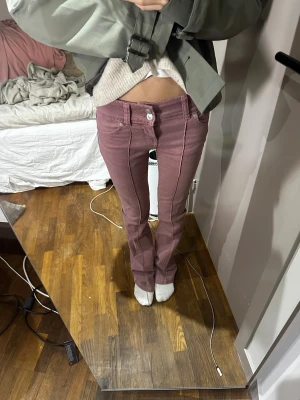 Ljuslila bootcut jeans med söm - Snygga ljuslila jeans med bootcut passform och markerad söm framtill. Byxorna har låg midja och klassisk femficksdesign. Materialet är jeans och de har en knapp och dragkedja i midjan. Perfekt för dig som gillar en unik färg och cool siluett. Från bershka. Använda en gång 
