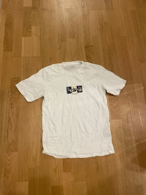 Vit t-shirt Jack & Jones Originals S - Vit t-shirt från Jack & Jones Originals i storlek small. Framsidan har ett tryck med svartvita grafiska rutor och text. Klassisk rund hals och korta ärmar. Materialet är mjuk bomull, perfekt för en chill och enkel stil.