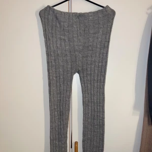 Grå ribbade stickade leggings - Mysiga grå stickade leggings med ribbad struktur och smal passform. Perfekta för chill dagar eller när du vill ha något extra bekvämt. Materialet är mjukt och värmande, och färgen är neutral så de passar till det mesta.