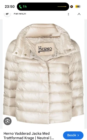 Beige pufferjacka från Herno - Snygg beige pufferjacka från Herno med trattformad krage och quiltad design. Jackan har en stilren look med breda horisontella kanaler och en stor etikett på insidan av kragen. Perfekt för dig som gillar minimalistisk och modern stil.