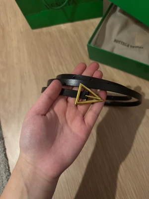 Svart skärp från Bottega Veneta - Supersnyggt svart bälte från Bottega Veneta med en unik trekantig guldfärgad metallspänne.