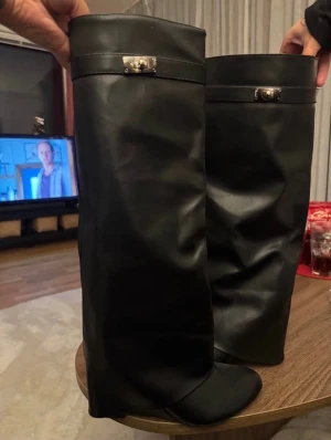 Svarta höga klackar i skinn med spänne  - Trendiga höga svarta klackar med spänne i sidorna ”folded boots”. Dessa är aldrig använda, köpta för 699, säljer för 300, (plus frakt) storlek 39. 