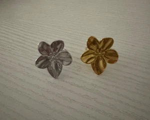 Blomformade ringar i guld och silver ( rostfria) - Två stora ringar i form av blommor, en i guld och en i silver. Båda har fem kronblad med fina detaljerade ådringar som ger en cool och unik look. Perfekt statement-accessoar för dig som gillar att sticka ut med smycken.( Styck pris 99kr )