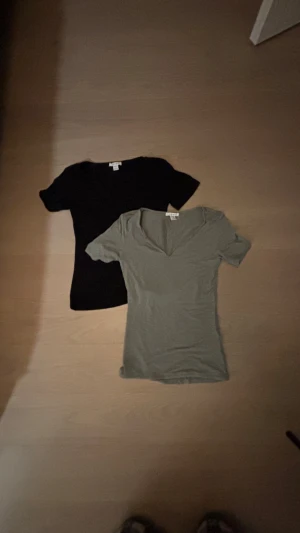 KÖP 2 BETALA FÖR 1 - Två stilrena t-shirts från Gina Tricot i svart och khakigrönt. Båda har v-ringning och korta ärmar, tillverkade i mjuk bomull. Perfekta basplagg med normal passform som funkar till allt. Säljes som paket!