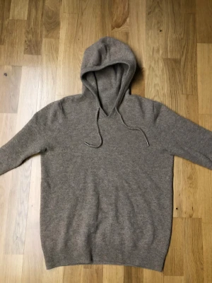 Beige hoodie i kashmir med huva - Mjuk och skön beige hoodie i kashmir med huva och snörning. Tröjan har långärmade ärmar och ribbade muddar vid nederkant och ärmslut. Perfekt för dig som gillar chill och stilren look. Helt ny använd 1 gång säljer för den är för liten👌🏻, storlek är S