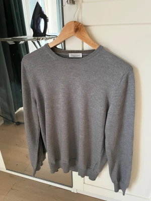 Grå stickad tröja Gran Sasso - Snygg grå stickad tröja från Gran Sasso, tillverkad i Italien. Tröjan har rund hals, ribbade muddar och är långärmad. Perfekt för dig som gillar stilrena och klassiska plagg med skön passform. Passar lika bra till jeans som till chinos. Storlek 50 vilket motsvarar M. Nyskick men ej ny