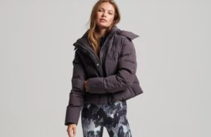 Mörkgrå lila pufferjacka från Superdry - Säljer en mörkgrå lila  pufferjacka från Superdry med hög krage och dragkedja framtill. Jackan är vadderad och har en oversized look, perfekt för kalla dagar. Superdry-logga på ärmen ger en clean och sportig vibe.
