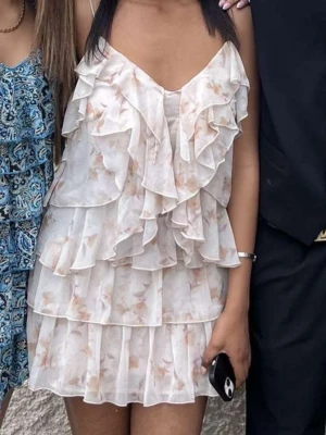 Ljus blommig volangklänning - Supersöt kortklänning i ljusa toner med blommigt mönster och flera lager volanger. Klänningen har tunna axelband och v-ringad urringning, använt bara en gång