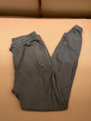 Ljusblåa mjukisbyxor från Morris, M - Snygga ljusblåa mjukisbyxor från Morris med elastisk midja och dragsko. Byxorna har en diskret ficka med dragkedja och en liten broderad patch på benet. Perfekta för chill dagar eller när du vill vara bekväm men ändå se fräsch ut.