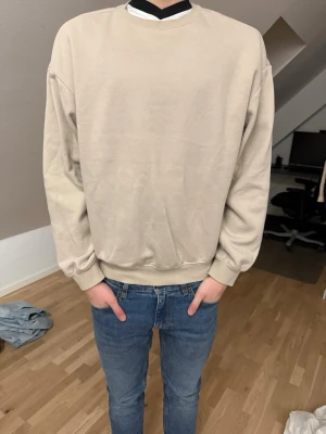 Tröja - Enkel och stilren beige sweatshirt i mjuk bomull. Tröjan har rund halsringning, ribbade muddar vid ärmslut och nederkant samt en relaxed passform. Perfekt för dig som gillar minimalistisk stil. Använd 2 gånger, som helt ny