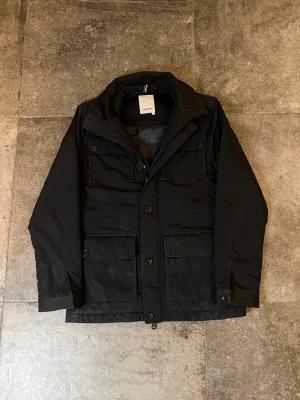 J.Lindeberg Feildjacket - Tja! säljer min riktigt schyssta j.lindeberg feild i strlk M👏 denna är perfekt nu till de kallare tider och kan säkert ta dig hela vägen in i tidig vår🫡 Som ni ser på bilderna finns några defekter som att vissa knappar lossnat och att det finns en mindre fläck (som inte syns i vanligt ljus) 🙏 tveka inte på att skriva ifall ni har fler frågor!