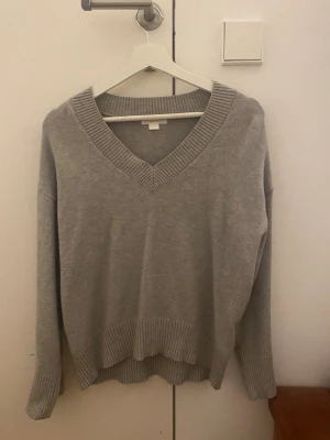 Grå stickad tröja Gina Tricot - Mysig grå stickad tröja från Gina Tricot med bred ribbad v-ringning, muddar vid ärmslut och nederkant. Säljer den eftersom att den inte kommer till användning och är som ny🩷 Skriv gärna om frågor/fler bilder