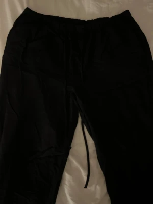 Svarta linnebyxor från Gina Tricot - Svarta linnebyxor från Gina Tricot med resår i midjan och snörning. Byxorna har en loose passform och är tillverkade i ett mjukt material. Använt 2-3 gånger. 