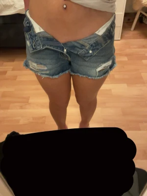 Blå jeansshorts med slitningar - Säljer ett par blå jeansshorts med rå kant och slitna detaljer framtill. Klassisk femficksmodell med dragkedja och knapp. Går att styla på olika sett. Perfekta för sommaren, köpta i Italien så märket är okänk, vet ej💓Storlek 158 men går att göra mindre i midjan och passar även storlekarna runt, uppåt o neråt!