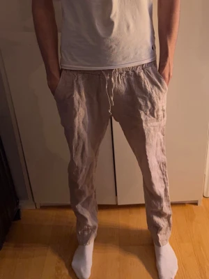 Beige linnebyxor från Befree, storlek L - Nypris 900kr. Säljer ett par chill beige linnebyxor från Befree i storlek L. Byxorna har elastisk midja med snörning och är gjorda i 100% linne. De har en loose passform och sidfickor, perfekta för varma dagar. Tillverkade i Italien.