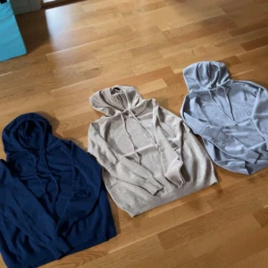 Kashmire hoodie i blå, grå och beige - Säljer tre stilrena hoodies med huva och snörning i färgerna marinblå, beige och ljusgrå. Alla har lång ärm och ribbade muddar vid ärmslut och nederkant. Perfekt för dig som gillar enkel och clean streetstil. Materialet känns mjukt och skönt mot huden. Storlek 158. Hör av er vid funderingar! 1200 för alla 350 för en. Pris kan diskuteras