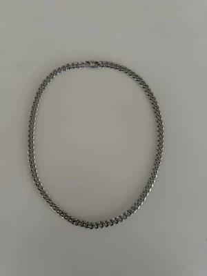 Kedjehalsband i silver från Edblad - Säljer ett kedjehalsband från Edblad i silverfärgad metall. Halsbandet har breda länkar och en stilren, robust känsla som passar perfekt till streetwear eller för att lyfta en enkel outfit. Låset är graverat med Edblad-loggan.