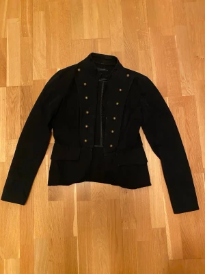 Svart jacka Vero Moda - Säljer en svart  jacka från Vero Moda i manchester. Jackan har dubbla rader med guldknappar framtill, markerad midja och fickor med lock. Långärmad och med snygga detaljer på ärmsluten. Perfekt för dig som vill ha extra bra stil.