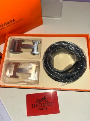 Herm bälte - Exklusivt svart bälte från Herm i äkta skinn med två utbytbara H-spännen i metall.  Snabb leverans stolek 120cm 