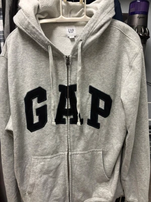 Gap zip hoodie - En grå stilren hoodie från gap med svart text i storlek m
