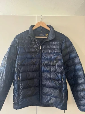 Ralp Lauren navy camo pufferjacka - Navy camo pufferjacka från Ralph Lauren. Funkar ner till minus grader. Litet hål på högerarm täckt med textillapp se bild. Utöver det inget slitage. Passar smal/medium