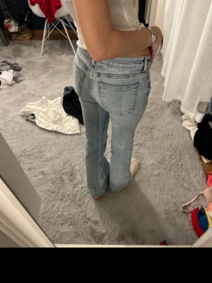 Ljusblå bootcut jeans - Säljer ett par ljusblå jeans med bootcut passform och låg midja. Klassisk femficksmodell i mjukt denimtyg, perfekta för dig som gillar en avslappnad men ändå snygg look. Snygga detaljer