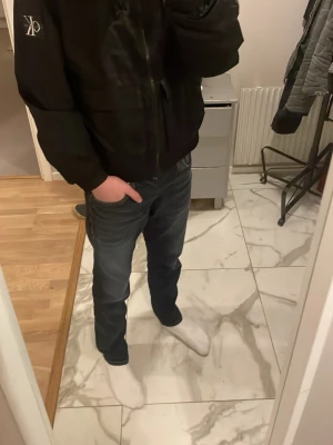 Svart vindjacka från Calvin Klein Jeans - Säljer en svart vindjacka från Calvin Klein Jeans med dragkedja framtill och huva. Jackan har en straight fit med CK-logga på bröstet och är tillverkad i ett lätt, syntetiskt material. Bra till vardags ock finare tillställningar.