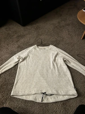 Tröja ifrån stronger  - En fin sandfärgad  tröja ifrån stronger. Man kan dra i bandet så den blir croppad 