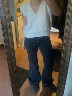 Vit stickad väst från Gina Tricot - Säljer en vit stickad väst från Gina Tricot i storlek L. Västen har en djup v-ringning, breda ribbade kanter och en loose passform. Perfekt att styla över en t-shirt eller skjorta för en chill look. Storlek L men sitter fint oversized på mig så skulle säga allt från xs-l beroende på önskad passform.