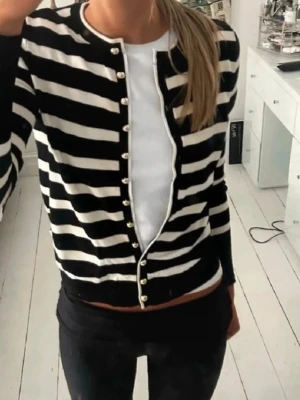 Randig kofta från Zara med pärlknappar - Säljer en mörkblå och vit randig kofta från Zara med snygga pärlknappar framtill. Storlek s. Den saknar en knapp (syns inte på de första bilderna då de togs innan knappen föll), det syns knappt när tröjan är på! För bild gå till sista! Slutsåld kofta!! 💗💗