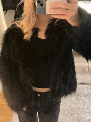 Svart pälsjacka med lång ärm - Säljer en svart fluffig pälsjacka med lång ärm och loose passform. Perfekt för dig som vill hålla dig varm under höst och vinter. 