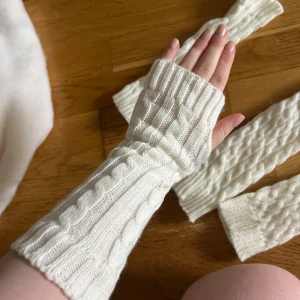 Vita stickade handledsvärmare och benvärmare - Säljer ett par vita stickade handledsvärmare med snyggt flätmönster och matchande benvärmare. De är långa och har tumhål, perfekt till vintern håller värmen perfekt sköna, oanvända.