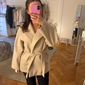 Beige kappa med bälte  - Säljer en beige kappa med bälte i midjan och bred krage. Från missay använd 1-2 gånger men inget man märker!