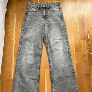 Gråa wide jeans från Gina Tricot - Säljer ett par gråa jeans från Gina Tricot, modell Perfect Jeans. De har hög midja och raka, vida ben för en avslappnad look. Klassisk femficksdesign och tillverkade i jeanstyg med snygg tvättad finish. Storlek 38. Använda ett fåtal gånger