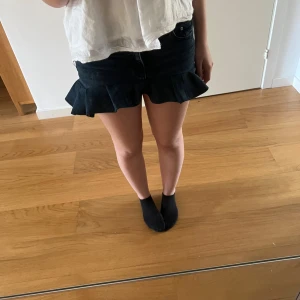 Svarta handgjord volangkjol - Säljer en handgjord jeanskjol från Gina Tricot i storlek 32. Kjolen har en snygg volangdetalj längst ner och klassisk femficksdesign.