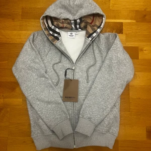 Grå Burberry hoodie  - Grå Burberry hoodie i storlek M. Den är i helt nytt skick och har aldrig använts.