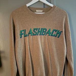 Beige stickad tröja Sandro med tryck - Beige stickad tröja från Sandro med  'FLASHBACK'-tryck i grönt. Knappt använd💕