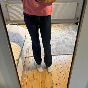 Mörkblå bootcut jeans - Snygga mörkblå jeans med bootcut passform och klassiska fickor både fram och bak. Jeansen har en låg midja och är tillverkade i mjukt denimtyg som sitter skönt. Perfekta för dig som gillar en tidlös och avslappnad stil.