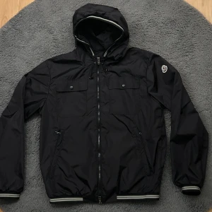 Moncler Vindjacka  - Helt ny. Jätte bra kvalitet. Storlek 3/L. Färg svart. Hör av dig vid minsta lilla fundering!
