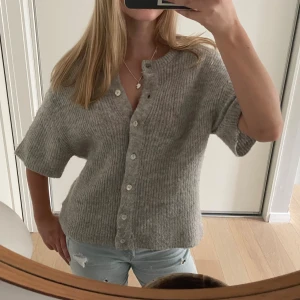 Grå ribbad kofta med kort ärm - Mysig grå kofta med ribbad struktur och korta ärmar. Köpte förra året och har använts några gånger men i fint skick. Skriv för fler bilder och pris kan diskuteras!💞