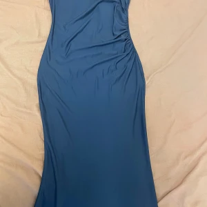 Lång klänning. Marinblå. Mörkblå. Shein - Snygg marinblå långklänning från Shein i storlek S. Klänningen har en figurnära passform med lätt rynkning på ena sidan för en cool detalj. Tillverkad i mjukt och stretchigt syntetmaterial. Har aldrig haft på mig den. Jag säljer den i nytt skick.