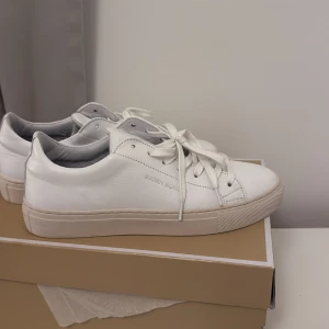 Vita sneakers från Björn Borg - Stilrena vita sneakers från Björn Borg i skinn med klassisk låg profil och rund tå. Skorna har vita snören, diskret logga på sidan och en platt sula i ljusbeige. Har använts 1 gång